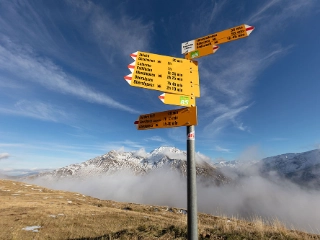 Verschiedene Wegweiser auf einem Wanderweg im Kanton Uri, im Hintergrund die atemberaubende Bergkulisse.